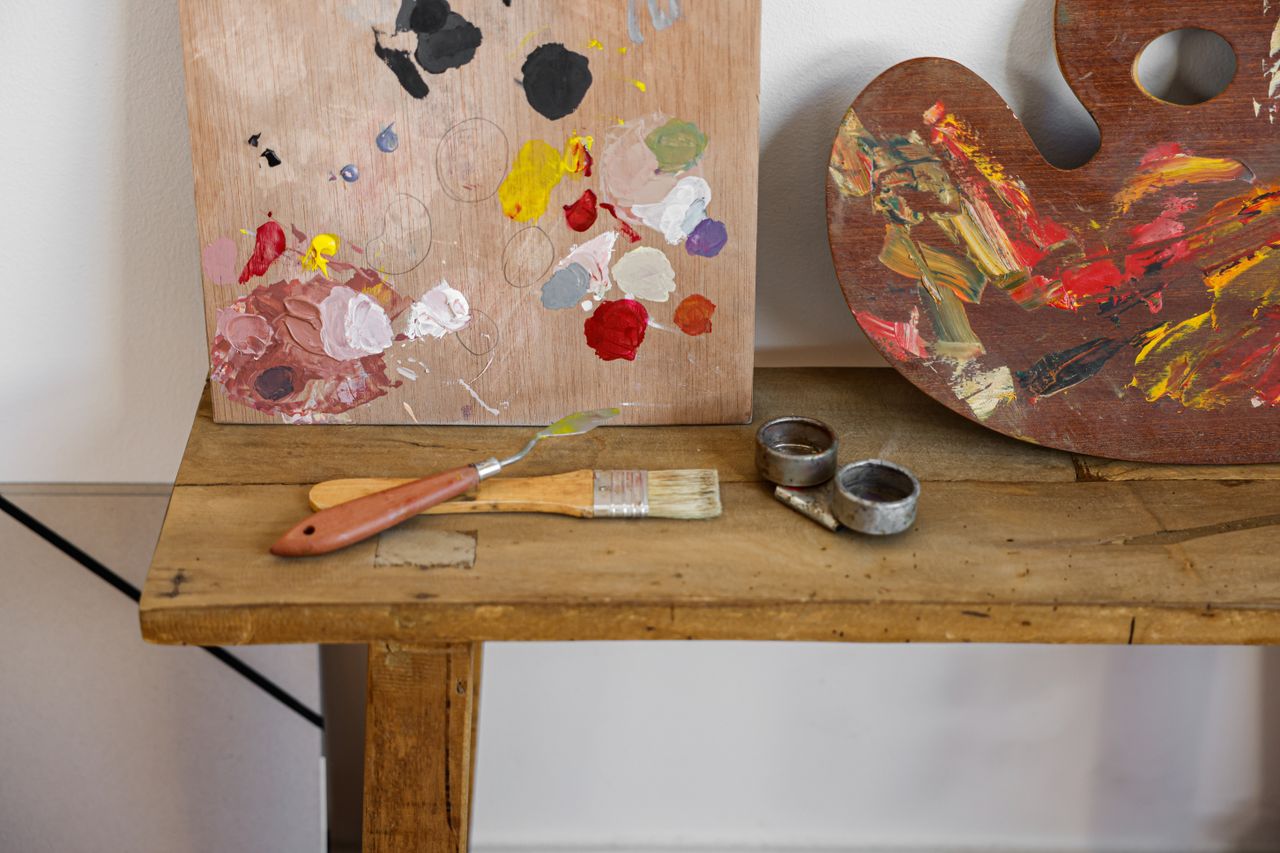 A colorful art studio table with paint palettes and brushes